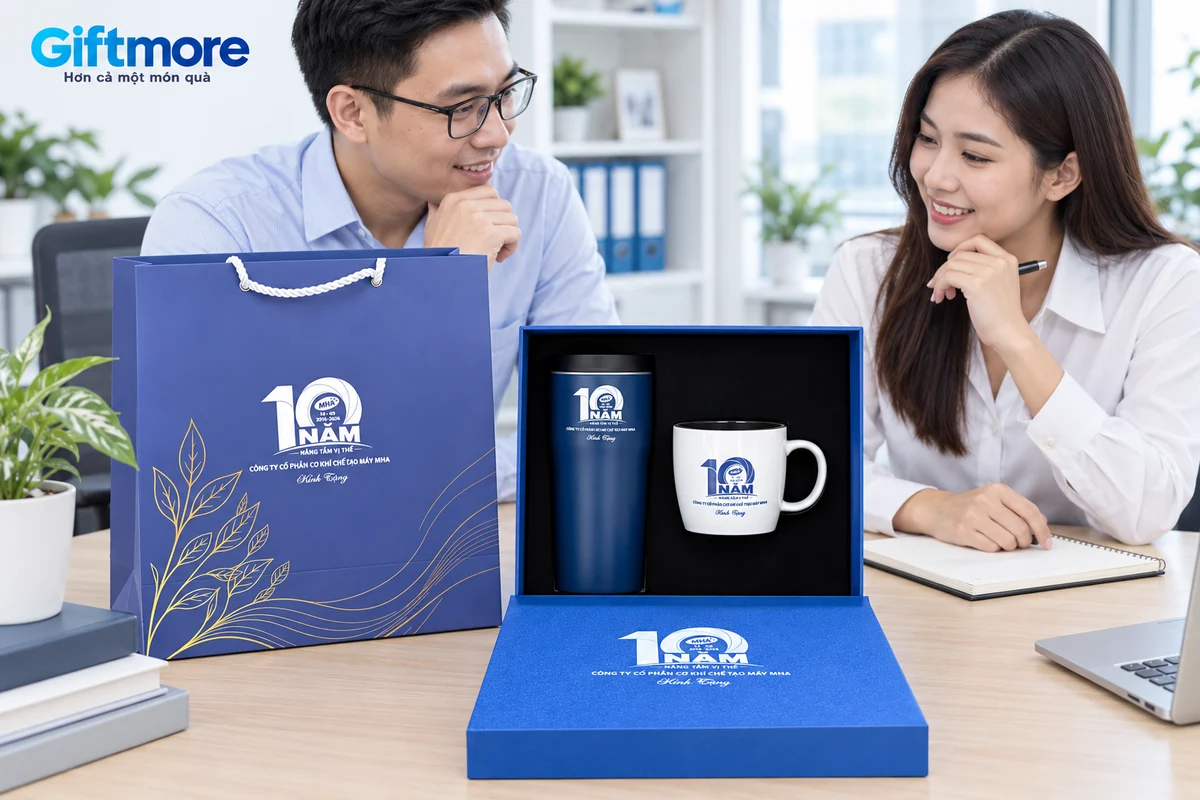 Hai người trao đổi cạnh bộ quà bình và cốc in dấu mốc mười năm