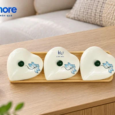 Ba hũ mứt tim sen xanh xếp một hàng trên bàn cạnh sofa và hai chén trà