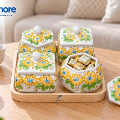 Bộ hũ mứt hoa vàng trên bàn trà với một hũ lục giác mở và nắp đặt cạnh