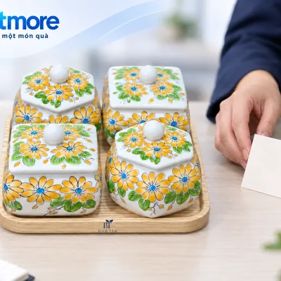 Người lớn đặt thiệp bên bộ bốn hũ mứt hoa vàng có demo BÌNH TÂM trên khay