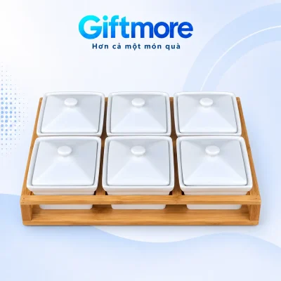 Sáu hũ mứt chữ nhật trắng đóng nắp xếp hai hàng trên khay gỗ có khe bên