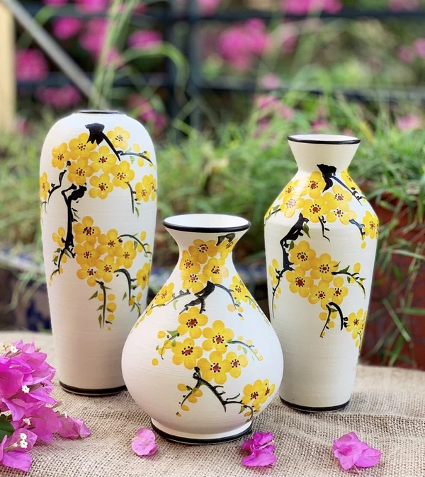 Ảnh gốc bộ ba lọ hoa vàng viền đen bày trên vải thô
