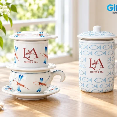 Mô phỏng phin sứ chuồn chuồn đặt trên cốc cà phê và đĩa, cạnh cốc sứ cá có nắp