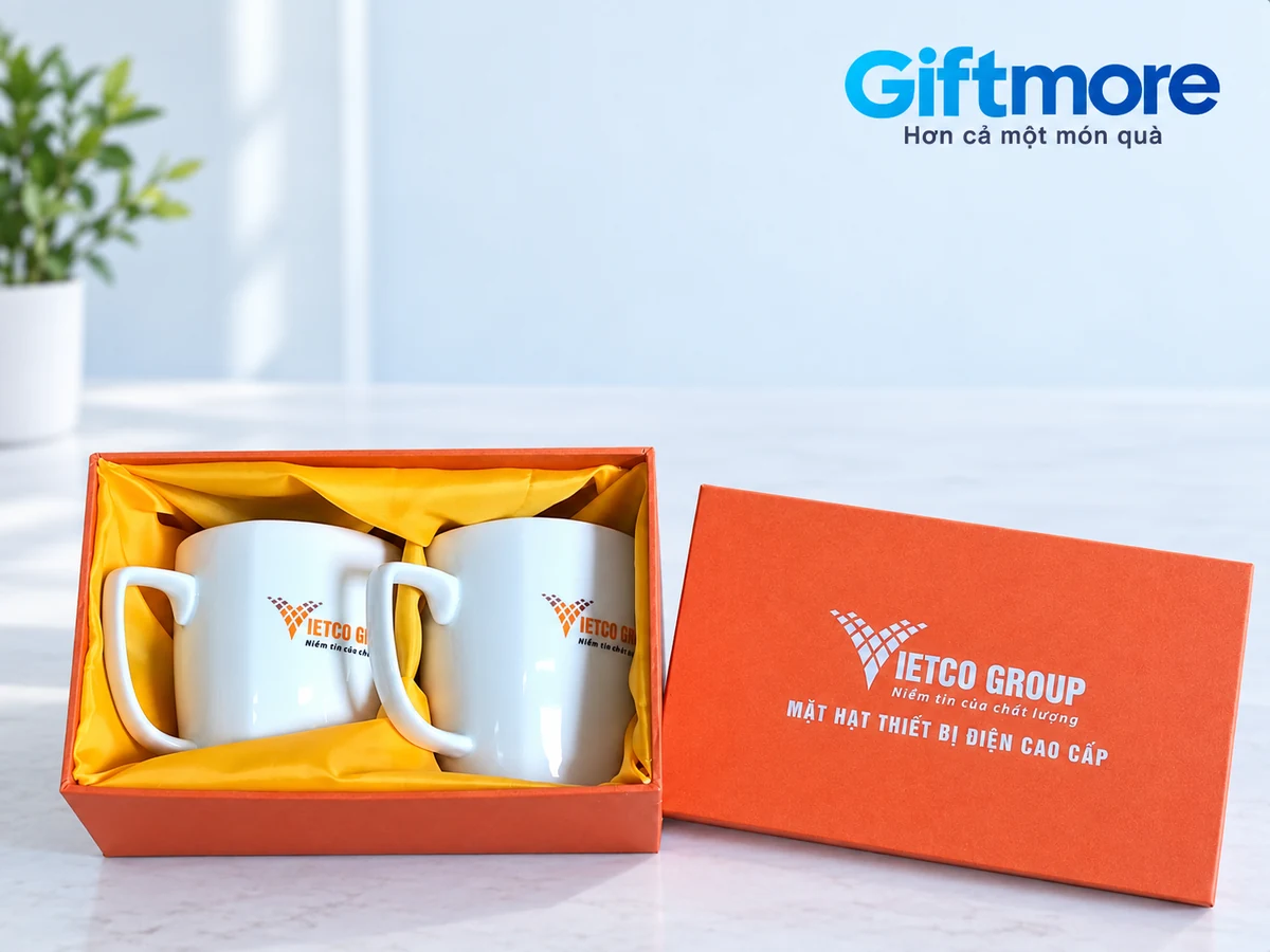 Hai ly trắng in VIETCO GROUP nằm trong hộp cam lót vàng, ảnh thật chỉnh nền
