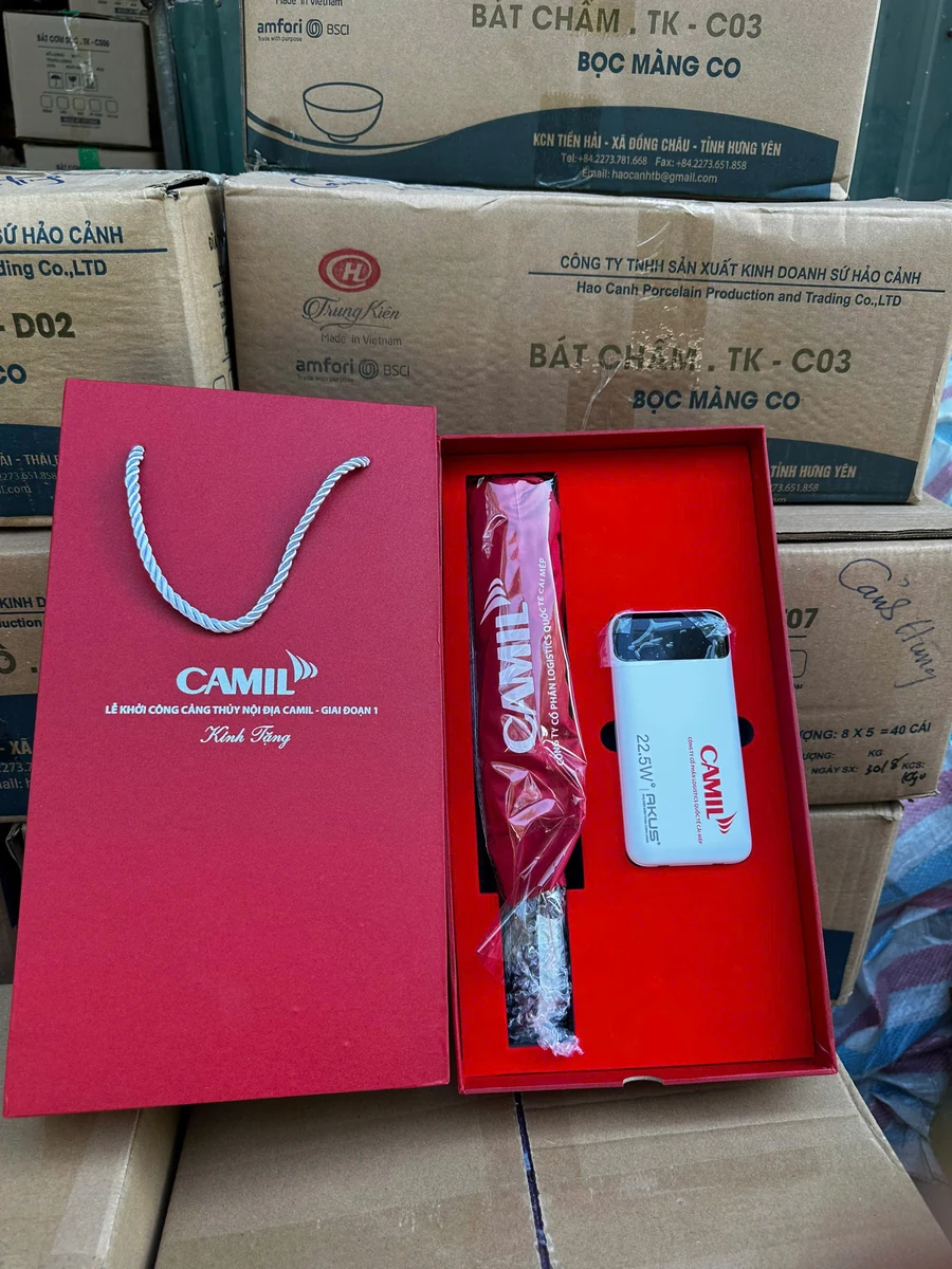 Ô gấp và sạc in CAMIL nằm trong hộp đỏ cạnh túi giấy có quai