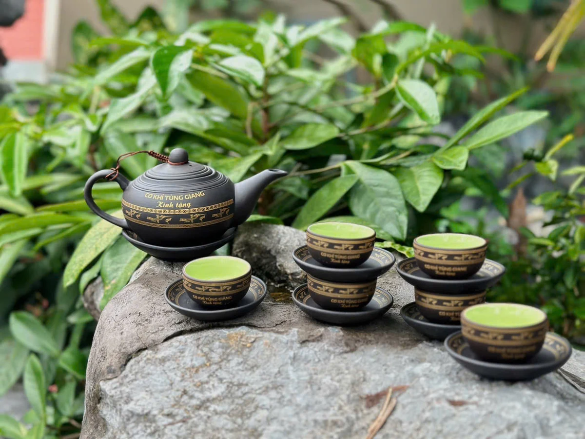Bộ trà tối màu với nhận diện Cơ khí Tùng Giang và hoa văn vàng trong ảnh thật
