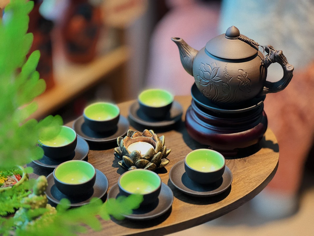 Mẫu ấm nâu hoa sen khắc với chén lòng xanh trong ảnh sản phẩm thật
