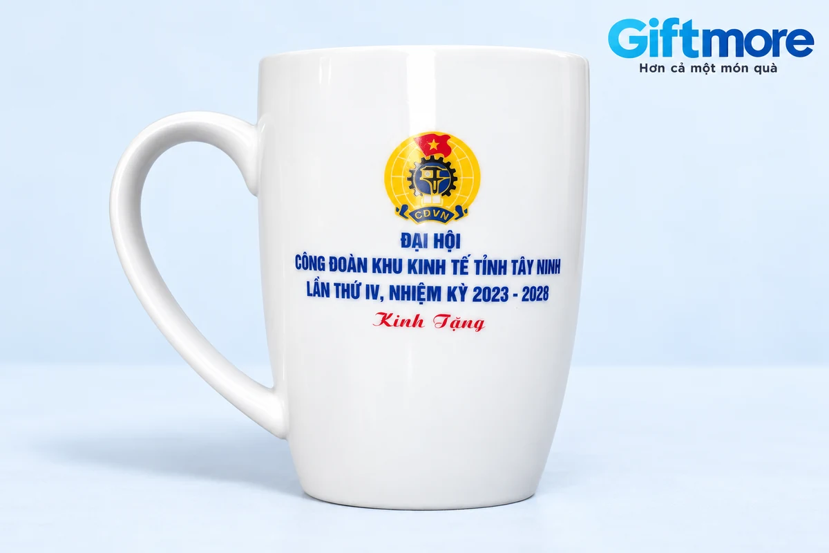 Cốc trắng in tên công đoàn và nhiệm kỳ trên nền xanh nhạt