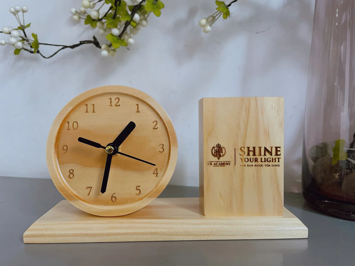 Ảnh nguồn đồng hồ tròn và ống bút gỗ có nội dung khắc trên mặt ống
