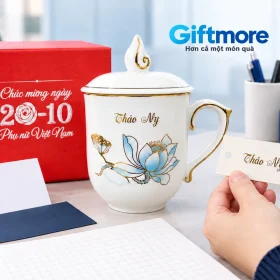Ly trắng có tên Thảo My cạnh hộp đỏ và thẻ tên được cầm để đối chiếu