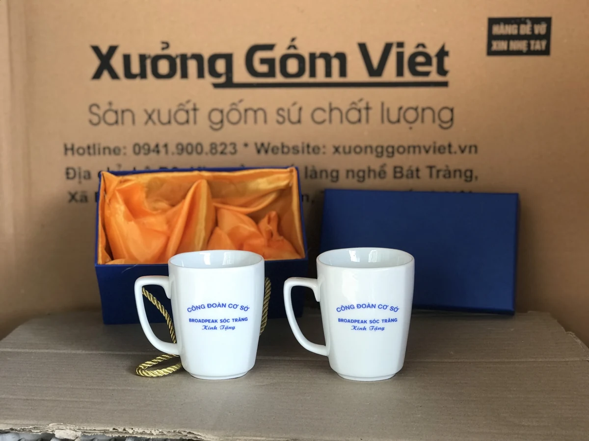 Hai ly trắng in nhận diện cùng hộp xanh lót vàng trong ảnh nguồn