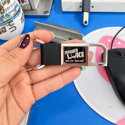Móc khóa kim loại 01 cầm trên tay với nhận diện Happy LUKE trong tư liệu