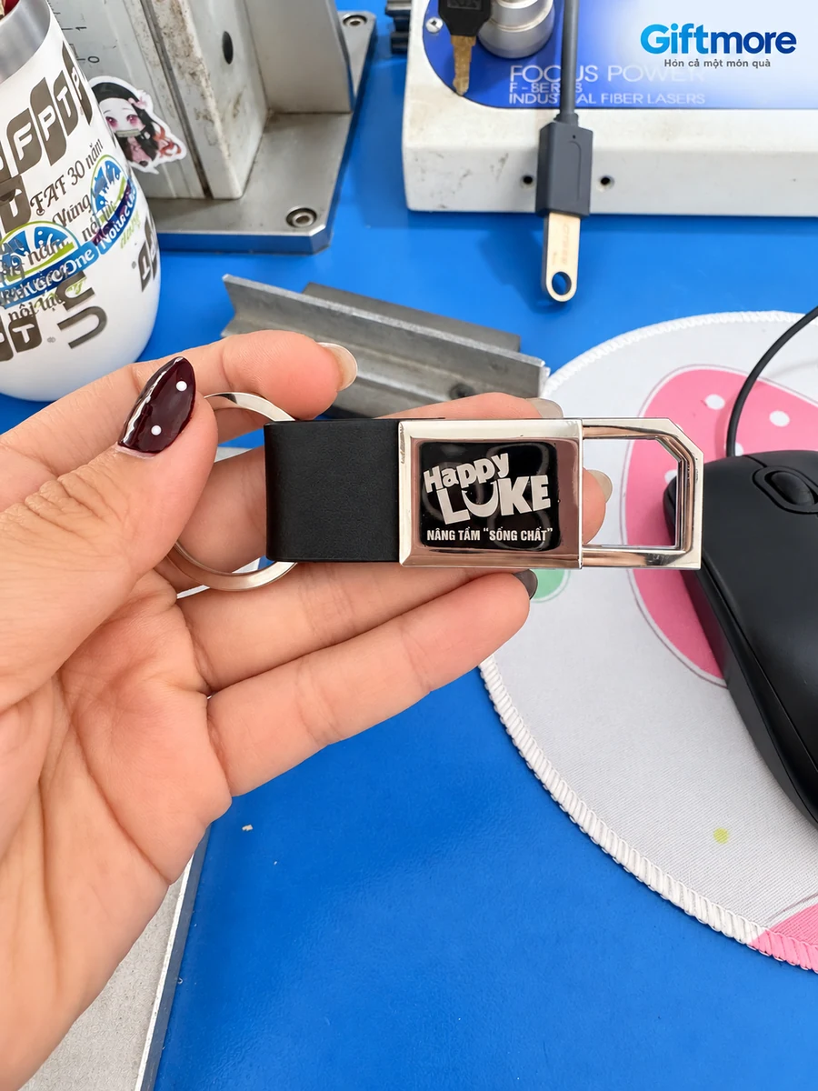 Móc khóa kim loại 01 cầm trên tay với nhận diện Happy LUKE trong tư liệu