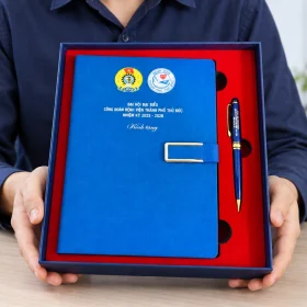 Người phụ trách cầm hộp sổ xanh và bút có nhận diện công đoàn bệnh viện