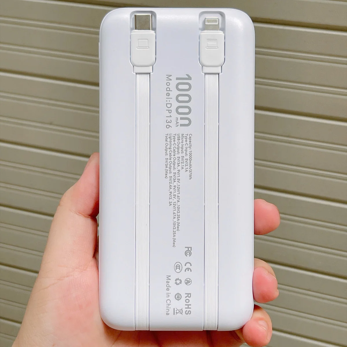 Ảnh thật mặt sau AKUS DP136 trắng với nhãn model 10.000 mAh và hai đầu dây cất trong rãnh