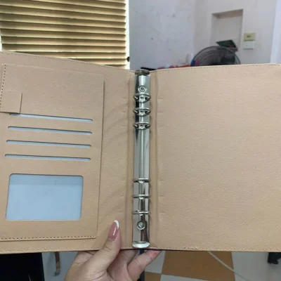 Ảnh tư liệu sổ còng mở màu be với sáu còng và các khe đựng thẻ ở bìa trái