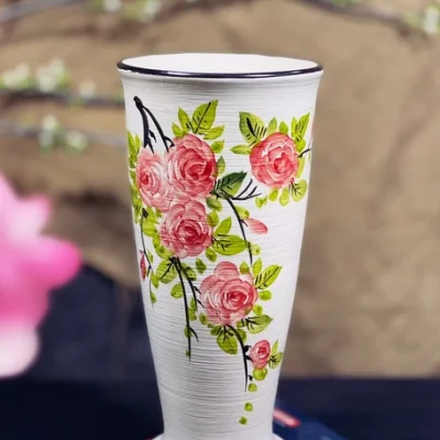 Ảnh thật một lọ dáng Cúp hoa hồng đỏ hồng, lá xanh và đường xước ngang trên nền trắng