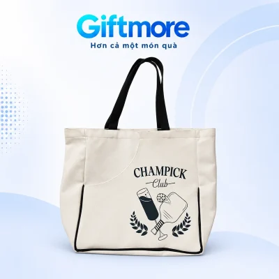 Túi canvas kem quai bản đen và viền đáy đen, hình CHAMPICK Club theo mẫu nguồn trên nền GiftMore