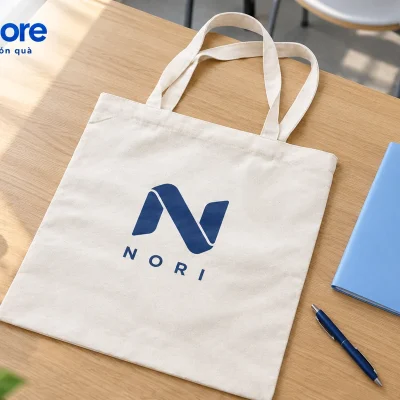 Mô phỏng chuẩn bị túi canvas mộc demo NORI cạnh tập tài liệu trên bàn đào tạo