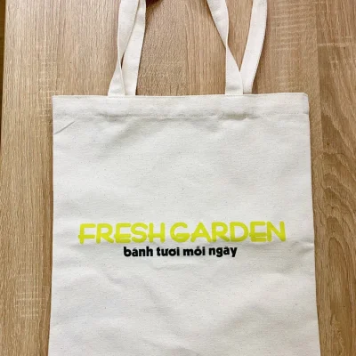 Ảnh thật túi canvas mộc FRESHGARDEN trên sàn gỗ, hai quai cùng màu và mặt vải nhìn rõ