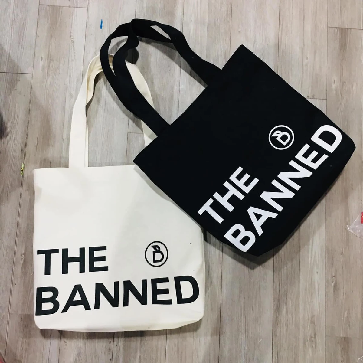 Ảnh gốc hai túi kem và đen in THE BANNED với quai cùng màu thân túi