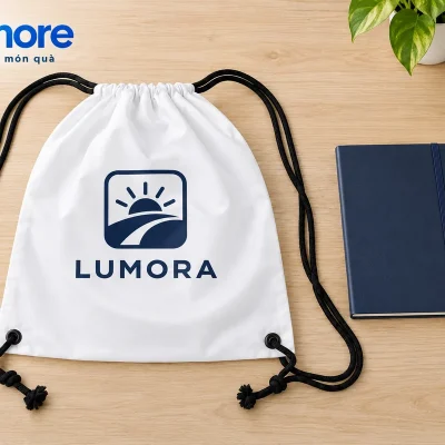 Mô phỏng đặt sổ và bút cạnh túi rút canvas trắng dây đen demo LUMORA để thử cấu hình đồ mang theo